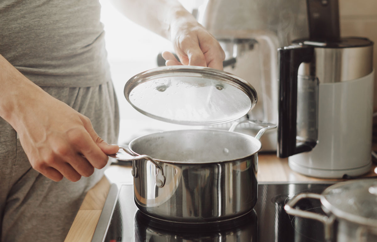 Joven cocinando y tapando una olla para conseguir eficiencia energética
